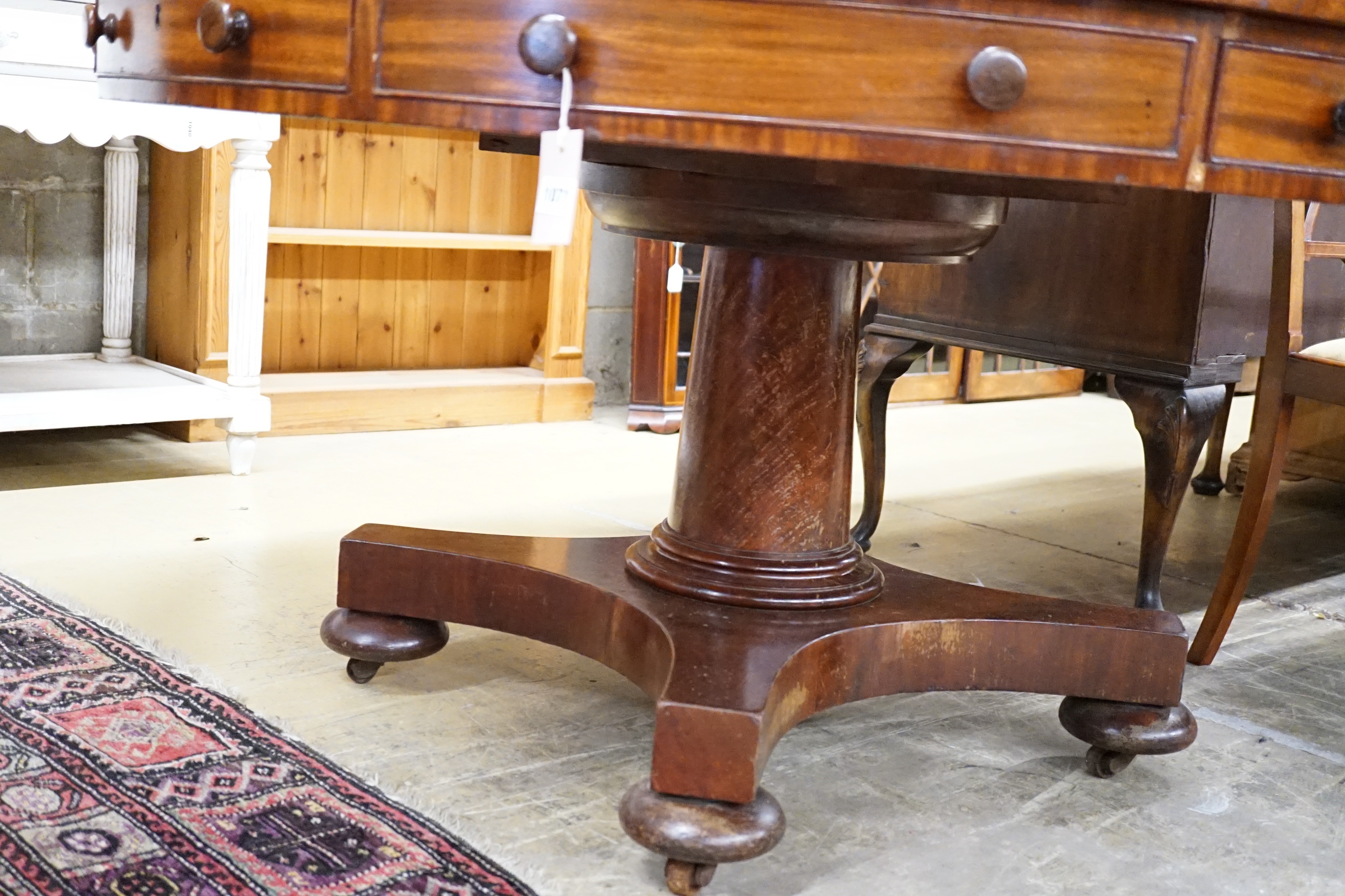 An early Victorian flame mahogany drum top ‘rent’ table, fitted four drawers on turned column saltire platform and brass castors, diameter 138cm, height 74cm